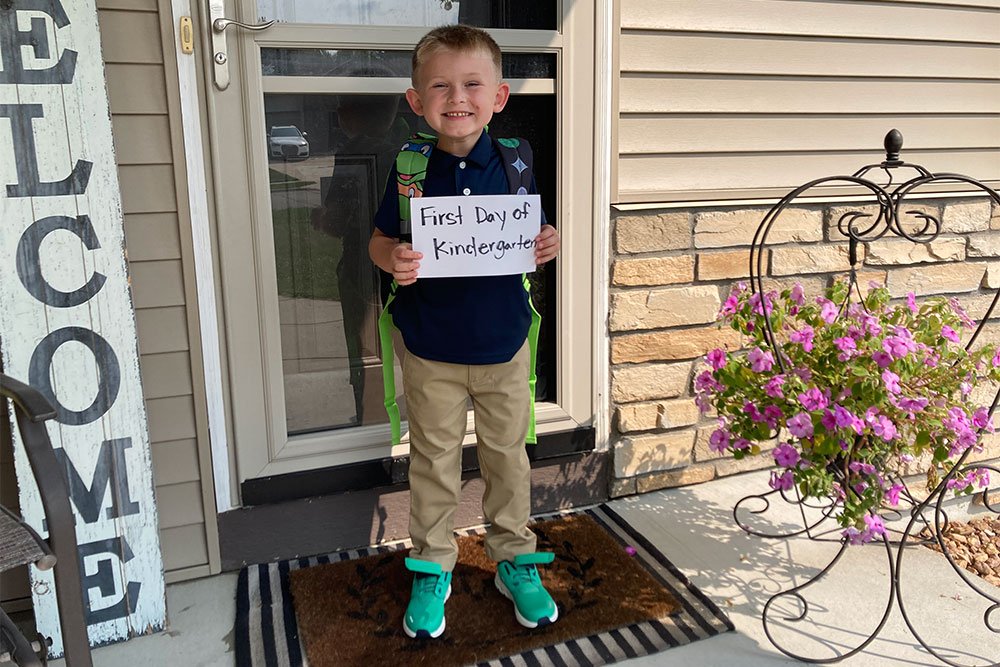 photo of a boy holding a sign in front of a door