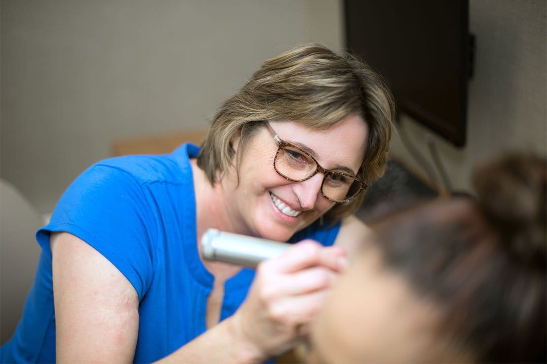 photo of Kari Mobley, AuD examing a patient's ear