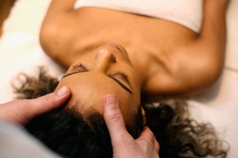 photo of a young woman getting a head massage therapy.