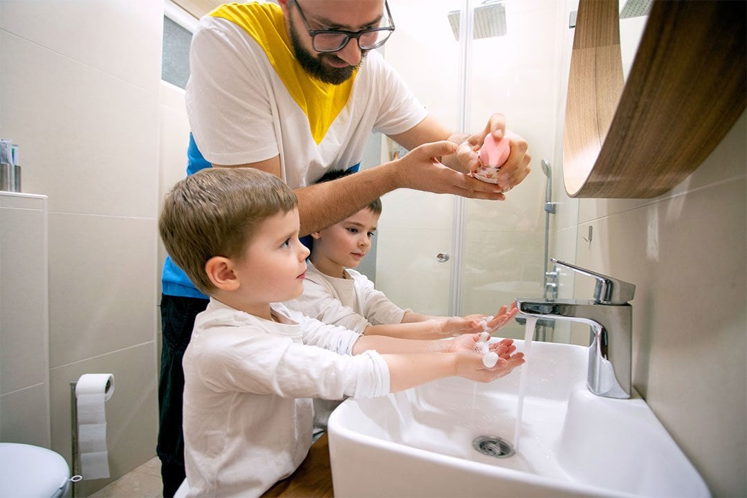 photo of a dad washing hands with his 2 boys in a bathroom