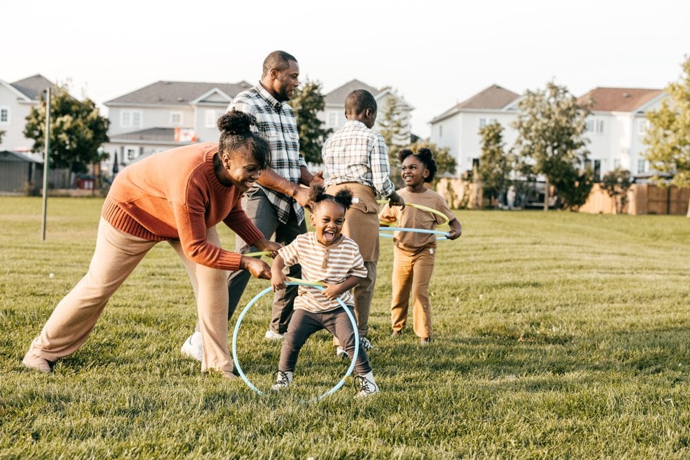 photo of a family playing hula hoop in the yard