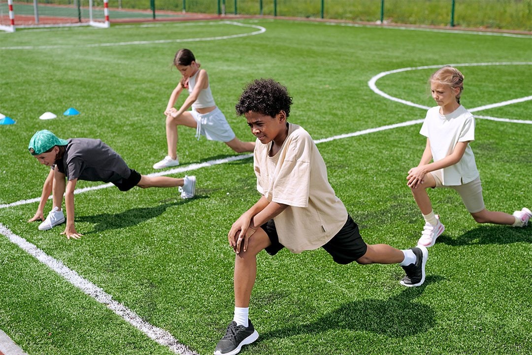 photo of 2 boys and 2 girls warming up in a field