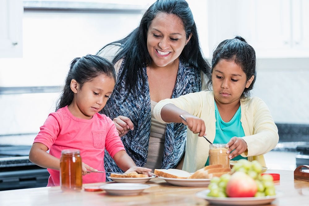 photo of a mom helping her 2 daughter preparing lunch