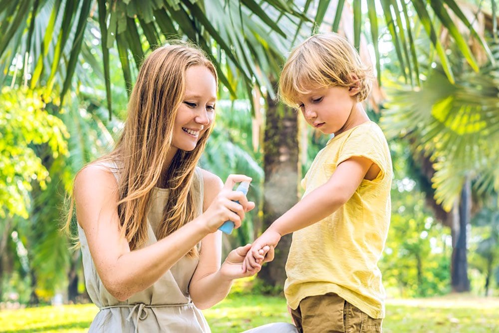 photo of a mom applying bug spray on her little boy's arm