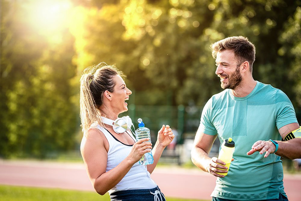 photo of a young couple hydrating while working out outdoor