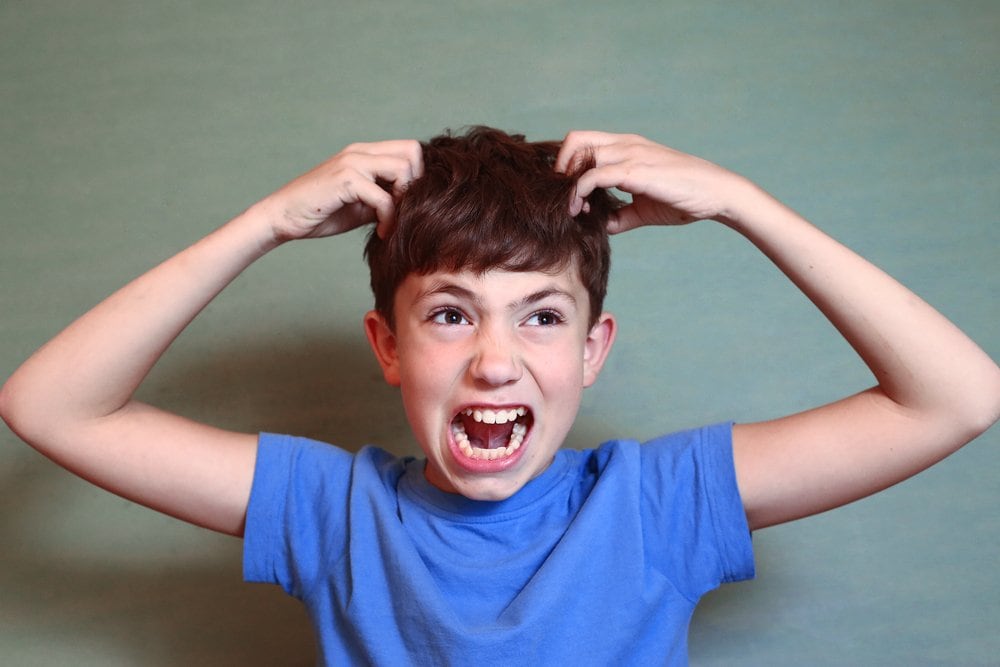 photo of a boy scratching his head