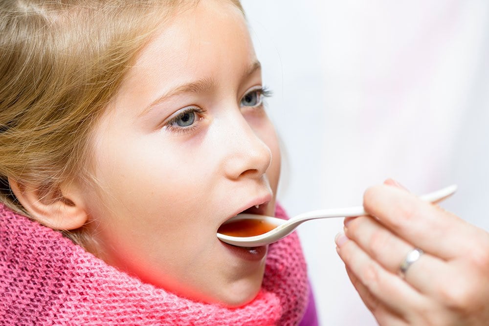 photo of a girl taking medicine from a spoon