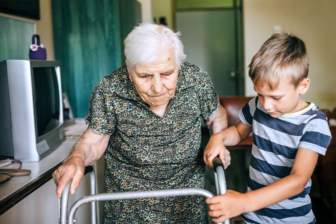 photo of a boy helping an elderly woman with a walker