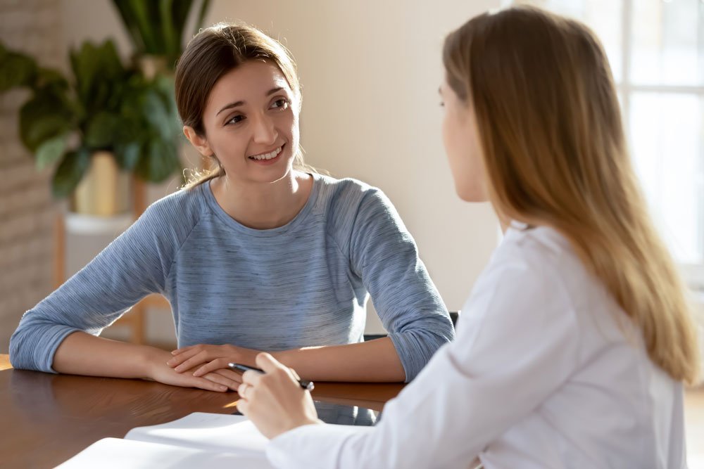 photo of a young lady patient talking to a clinician