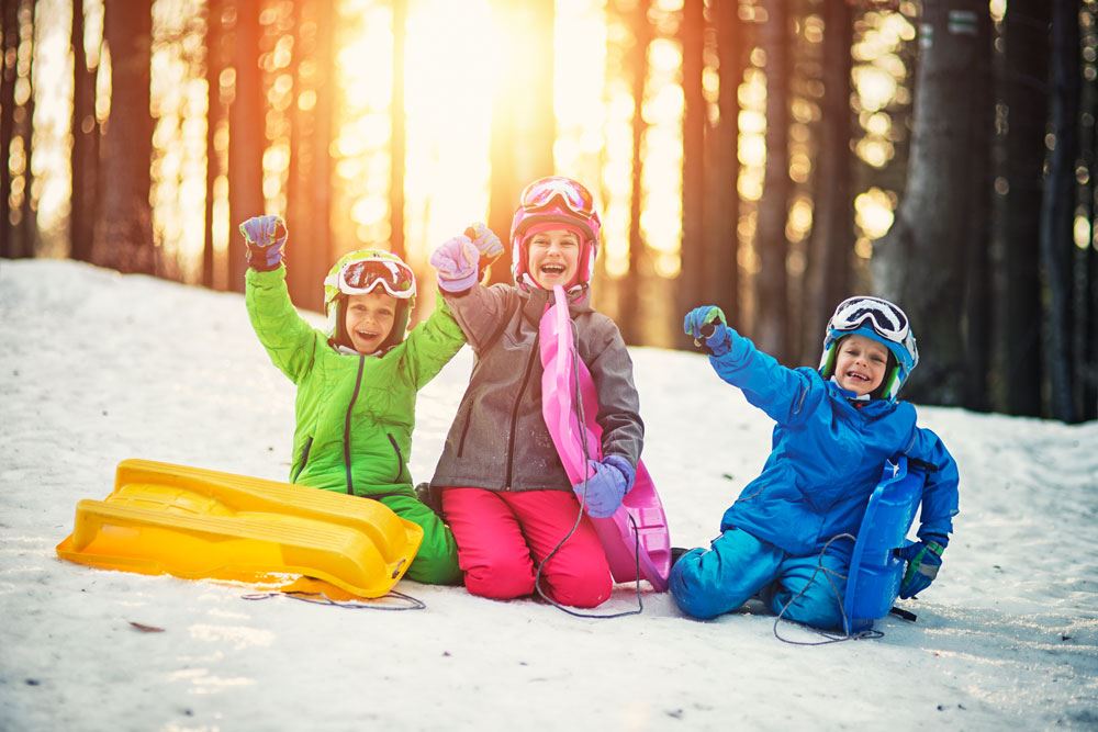 photo of 3 kids snow sliding outdoor