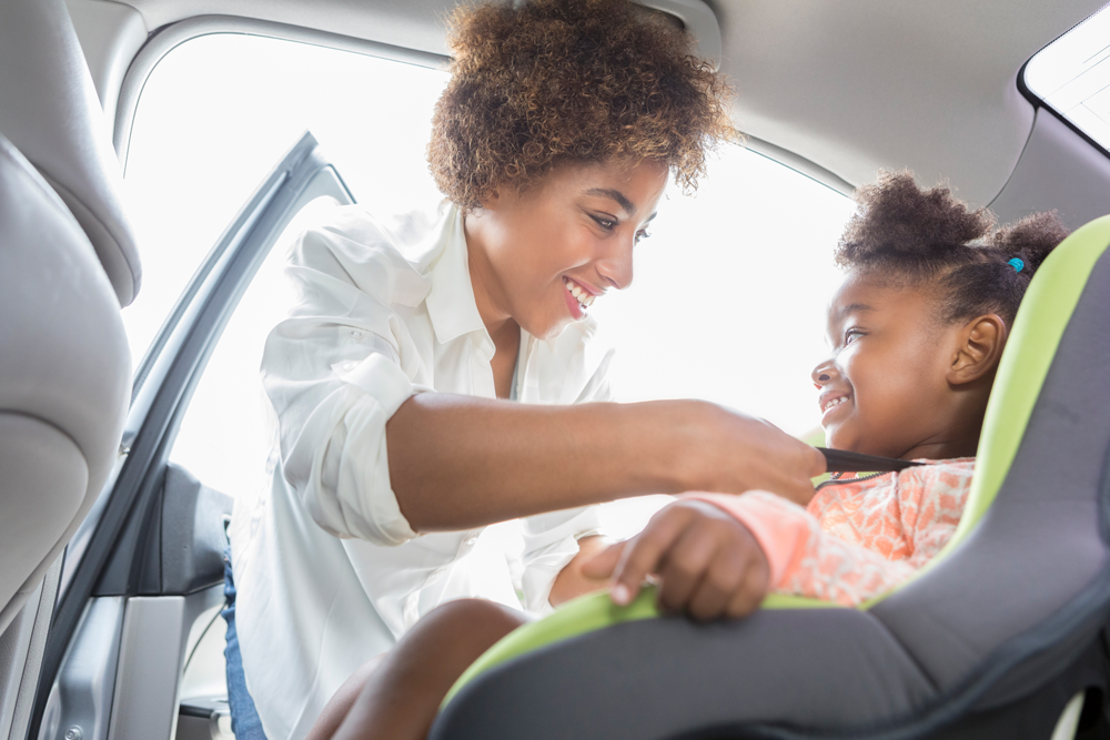 Mom buckling child into car seat